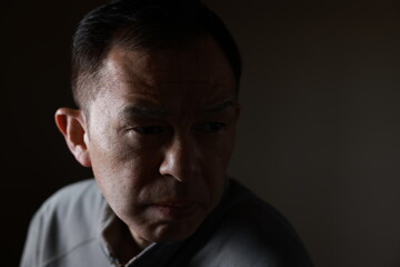 Middle-aged Japanese man in gray casual shirt on gray background. Conceptual image of world peace, stability in daily life, and sustainable living.