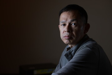 Fototapeta premium Middle-aged Japanese man in gray casual shirt on gray background. Conceptual image of world peace, stability in daily life, and sustainable living.