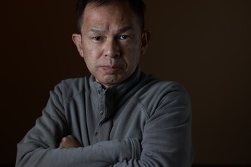 Fototapeta premium Middle-aged Japanese man in gray casual shirt on gray background. Conceptual image of world peace, stability in daily life, and sustainable living.