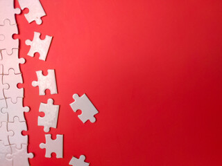 Unfinished white jigsaw puzzle pieces on red background