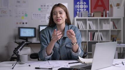 Young Asian female graphic designer blogger influencer talking looking at camera shooting education tutorial vlog training filming video course for social media at studio.