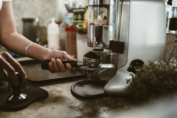 barista use bottomless filter with grinder machine at coffee shop. coffee maker concept.