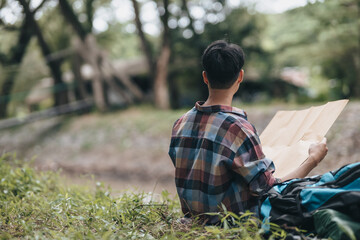 Lost hiker with backpack checks map to find directions near the river in the forest. hiking and adventure concept.