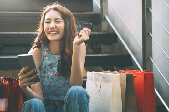 Happy young adult southeast asian woman with shopping bags on day