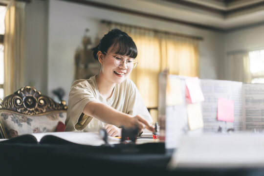 Young adult asian woman enjoying role playing tabletop storytelling and board game with miniatures