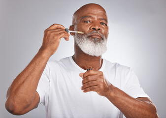 Senior man, face serum and skincare with dermatology and cosmetics for clean, glow and fresh skin. Portrait of a black male with a pipette for collagen oil on a grey studio background for beauty