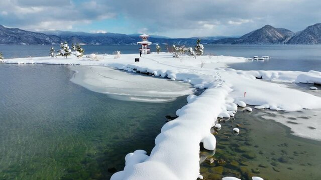 picturesque clear mountain lake in winter, aerial view of lake Toya in Hokkaido with a Japanese pagoda in the snow, scenic tranquil winter scene