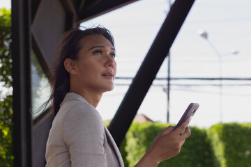 Sensual transgender person using mobile phone in urban city. Asian executive woman holding smartphone with confidence look outdoors. Communication, date concepts