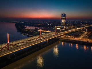 Budapest, Hungary - Aerial view of Rakoczi bridge above River Danube with traffic lights and Budapest's new skyscraper building (MOL Campus) at background at sunset. Blue and red sky at dusk
