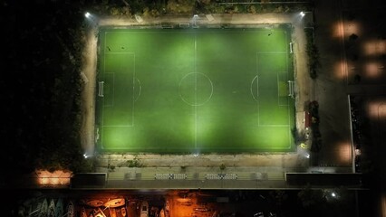 Drone footage flying away from an illuminated soccer field at night