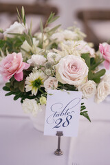 Wedding arrangements of flowers stand on a white tablecloth