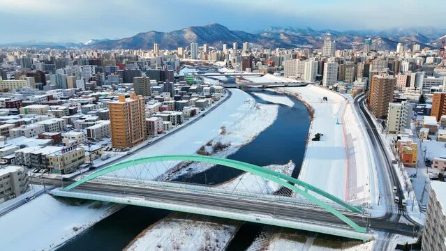 winter aerial view of Sapporo, Hokkaido, northern Japan, flying above frozen river in downtown Sapporo