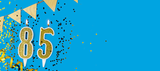 Golden candle number eighty five. Birthday or anniversary card with the inscription 85 on blue background. Anniversary celebration. Banner.