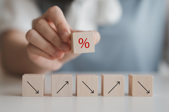 Hand hold percentage sign on wood block and arrow up and down. Interest rate increase or decrease and mortgage rates, business and financial growth, inflation, sale price and tax rise concept.