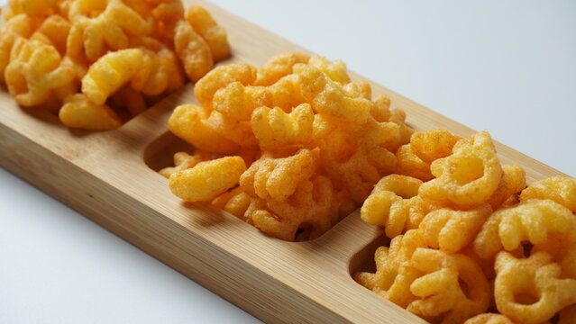 Cheetos Is A Crunchy Corn Puff Snack. Bright Orange Cheese Puffs In A Wooden Board.