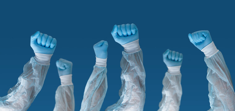 Portrait Of Medical Staff Wearing Face Masks With Hands Up And Holding A Sign That Says 