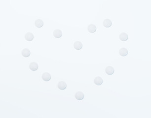 White pills displayed in the shape of a heart on white background