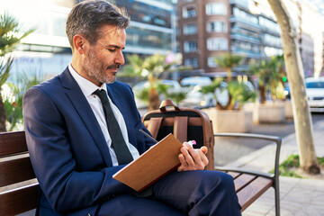 Businessman taking notes in notepad in city