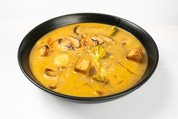 Tom yum. vegetarian soup in a black dish on a white background. a Thai dish