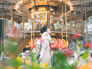 Portrait of asian woman at outdoor on winter in city with carousel Illumination night background