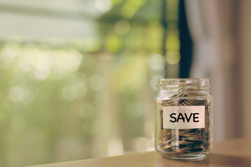 Coins in glass jar with SAVE word written text label for Education, Necessity, Play, Long Term, Give and Financial Freedom concept.