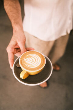 Café de barista con dibujo latte art hecho a mano y servido en taza y plato vintage. 