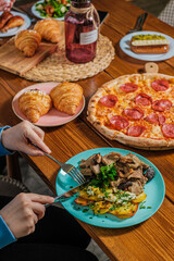 table filled with food with people's hands and a pizza in the middle