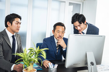パソコン画面を見ながら会議するビジネスマンのグループ