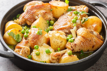 Italian American cuisine Chicken Vesuvio a skillet with potatoes, garlic, green peas closeup on the black pan on the table. Horizontal
