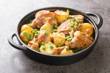 Chicken pieces with potato wedges and roasted in a lemon garlic white wine sauce close-up in a frying pan on the table. Horizontal
