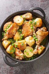 Homemade Baked Chicken Vesuvio with Peas and Potatoes closeup on the black pan on the table. Vertical top view from above