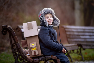 Little child, blond boy with pet dog, carying home on his back, kid, having paper house