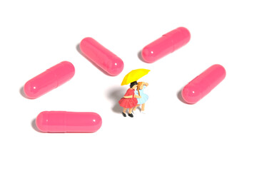 Miniature people toy figure photography. Two girls kid standing in the middle of pink drug pill vitamin for flu treatment. Isolated on white background