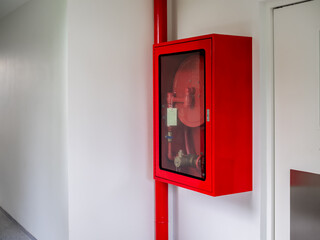 Fire extinguisher cabinet mounted on the wall in the corner of the white hotel building. Locked red...