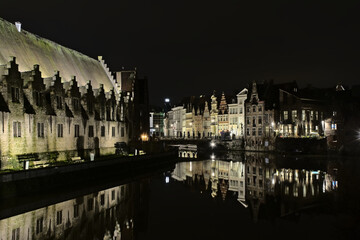 Fototapeta na wymiar illuminated buildings reflecting into the water of river Lys, touristic view in the city of Ghent, Flanders, Belgium
