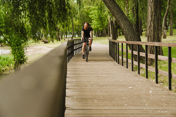 Adult handsome tattooed bearded man riding a bicycle in park