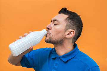 Handsome man drinks yogurt or milk on orange background. Mock up copy space