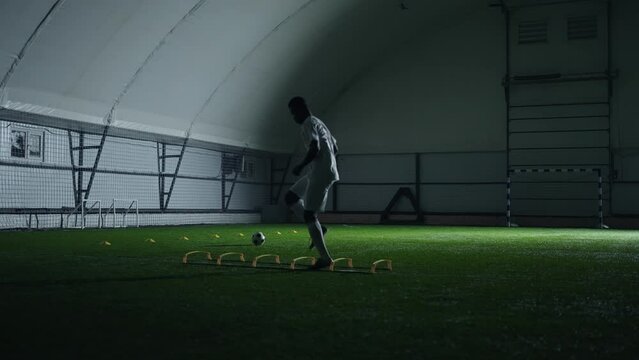 individual training of athletic black man football player in football pitch indoor, running, jumping