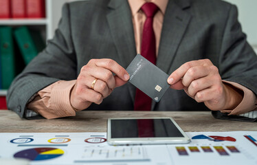 Male hands holding credit card and dollars using laptop.