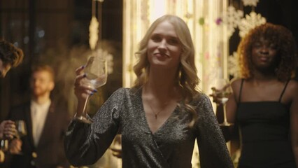 beautiful blonde woman with champagne glass in hand dancing and singing New year song in party - Powered by Adobe