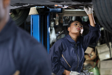 Group of car mechanic in uniform checking maintenance a lifted car service with clipboard at repair garage station. Worker holding wrench and fixing breakdown vehicle. Car repair service concept