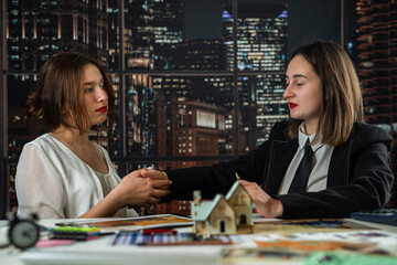 Fototapeta premium Two female architects teamwork to discuss and inspect the house designs with blueprints