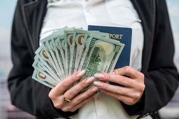 Young woman holding United States passport with dollar bills very happy in front of her chest.
