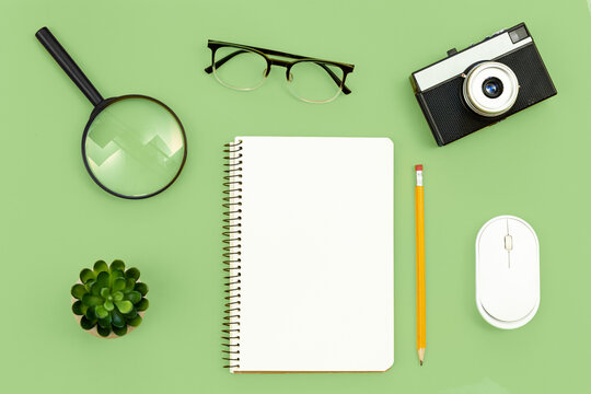 Minimal background with blank paper, camera, glasses, and magnifier, flat lay.