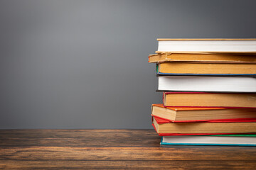 A stack of books in a colored cover and a book with old pages on a gray background. Education learning concept