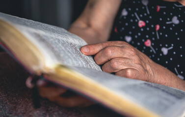 An old woman reads the Bible, hands close up.