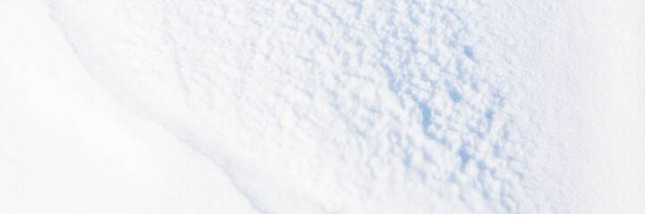 Fototapeta premium Beautiful winter background with snowy ground. Natural snow texture. Wind sculpted patterns on snow surface. Wide panoramic texture for background and design.