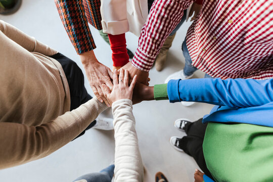 Diverse businessmen and businesswomen stacking hands in office