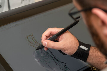 man holding a tablet and drawing with a pen in his hand
