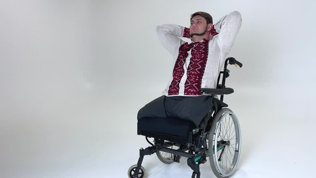adult man is sitting in wheelchair with hands behind head he raised head up thinks about something he dreams of remembering past he has no both legs Russian aggression in Ukraine